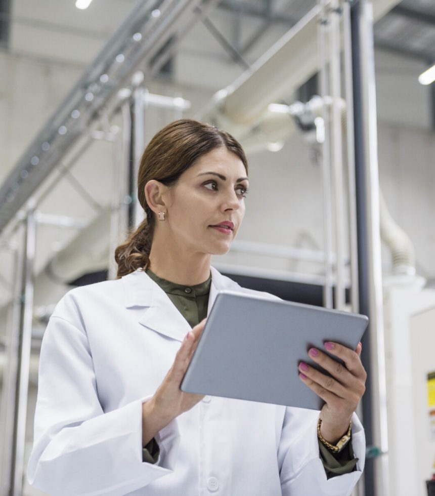 Woman checking manufacturing machines in high tech company, using digital tablet